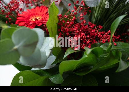 Primo piano di un bouquet con fiori rossi e foglie verdi diverse Foto Stock