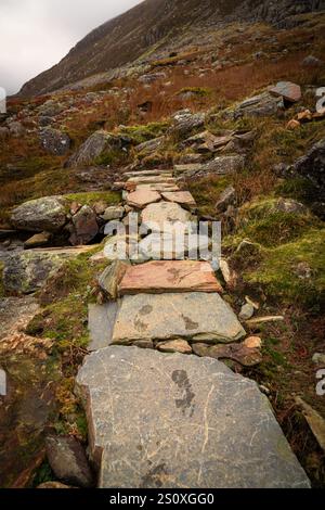 Sentiero in pietra che sale sulla montagna con impronte sulle rocce Foto Stock