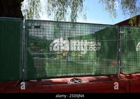 Rete di barriera verde retroilluminata per l'anello ferroviario suburbano, con il logo del progetto delle infrastrutture di trasporto, di fronte ai lavori di costruzione vicino a Clayton Rd Foto Stock