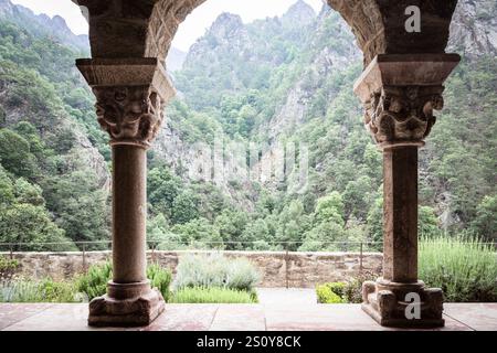 Pilastri del chiostro nel monastero di Saint Martin du Canigou nei Pirenei francesi di fronte al mistico scenario di montagna, Occitania, Francia Foto Stock