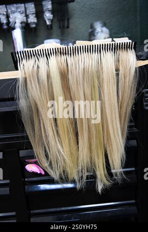 Le prolunghe bionde per capelli sono disposte in modo ordinato su un rack in un salone. Foto Stock