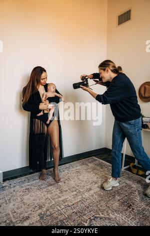 Fotografo che cattura una madre che tiene in braccio il bambino durante un servizio fotografico Foto Stock