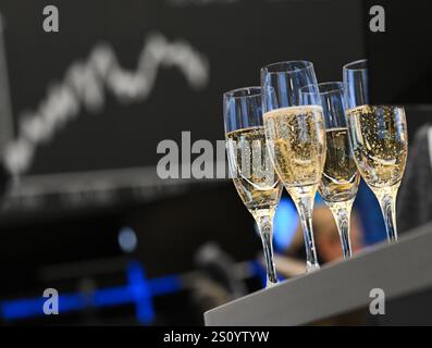 30 dicembre 2024, Assia, Francoforte sul meno: L'ultimo giorno di contrattazione dell'anno, i bicchieri da champagne sono pronti per un brindisi nella sala commerciale della borsa di fronte al Consiglio con la curva Dax. Gli esperti sono cautamente ottimisti alla fine di un forte anno di mercato azionario. Foto: Arne Dedert/dpa Foto Stock