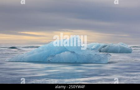 Iceberg dalla laguna glaciale di Jokulsarlon alla deriva nell'Oceano Atlantico settentrionale al tramonto, Islanda. Ripresa con esposizione lunga Foto Stock