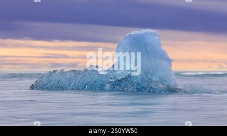 Iceberg dalla laguna glaciale di Jokulsarlon che galleggia nell'Oceano Atlantico settentrionale al tramonto, Islanda. Ripresa con esposizione lunga Foto Stock