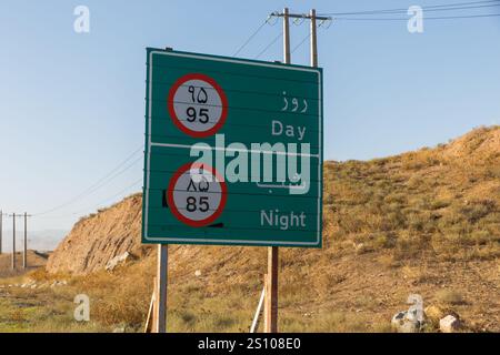 Un chiaro segnale del limite di velocità mostra diversi limiti per la guida diurna e notturna in una zona rurale dell'Iran, sottolineando la sicurezza stradale. Foto Stock