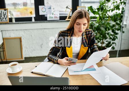 Donna d'affari attraente impegnata nel lavoro, nella revisione di documenti e nell'utilizzo del suo smartphone. Foto Stock