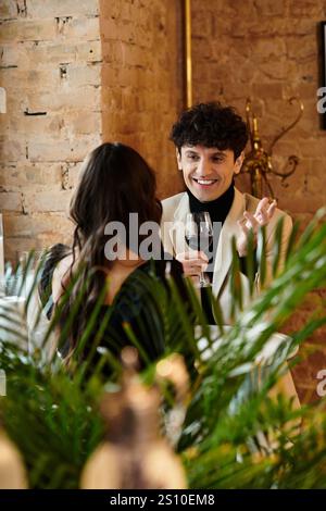 Una coppia gode di una cena romantica, ridendo e condividendo un bicchiere di vino in un accogliente ristorante. Foto Stock