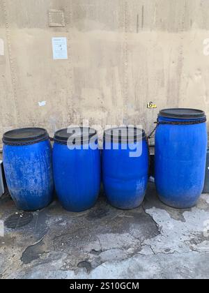 Quattro barili di plastica blu per l'olio usato su un patio Foto Stock