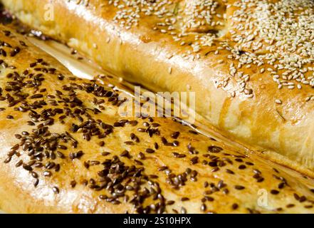 Torte di carne. Panini cotti con impasto lievitato, cosparsi di sesamo e semi di lino su pergamena. Primo piano, macro. Foto Stock