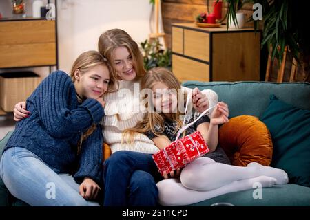 Una scena emozionante che raffigura una bella famiglia che condivide momenti piacevoli e gioiosi con un regalo di vacanza insieme Foto Stock