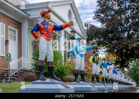 Saratoga Springs, New York, USA - 10-02-2024: Museo nazionale delle corse e Hall of Fame esposizione all'aperto di fantini di prato allineati lungo Union Avenue. Foto Stock