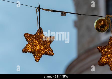 Grazioso ornamento illuminato a stelle appeso a una serie di luci, ornamento natalizio Foto Stock