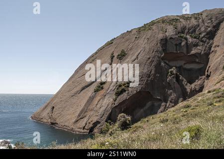 Vista panoramica di una formazione rocciosa unica che si innalza sopra una tranquilla baia oceanica, mostrando la bellezza della costa della sardegna Foto Stock