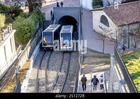 Lugano, Svizzera - 24 dicembre 2024: Una funicolare viaggia a fianco dei pedoni su una scala nella panoramica città di Lugano Foto Stock
