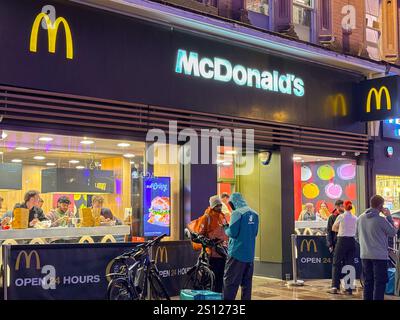 Cardiff, Galles, Regno Unito - 17 novembre 2024: Consegna in attesa di ordini fuori da una filiale del McDonald's nel centro della città di notte Foto Stock