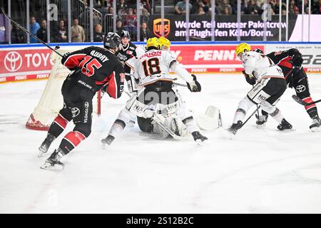 Eishockey DEL 24/25 - 31. Spieltag: Kölner Haie vs Löwen Frankfurt in der Lanxess arena am 30.12.2024 Frankfurts Torhüter Jussi Olkinuora (Nr.45) sitzt auf dem Puck, Kölns Joshua Currie (Nr.18) stochert nach foto: Osnapix Foto Stock