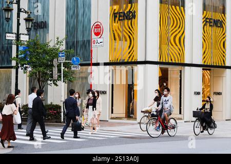 TOKYO, GIAPPONE - 26 maggio 2021: Ciclisti e pedoni che utilizzano un passaggio pedonale vicino a un negozio Fendi nel centro commerciale Ginza Six. Foto Stock