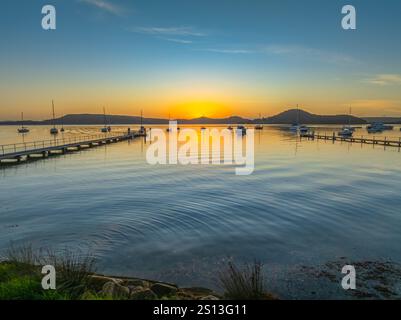 Alba sull'acqua di Brisbane, con cieli prevalentemente limpidi e una piccola nuvola luminosa alta intorno al Couche Park, Koolewong sulla costa centrale, NSW, Australi Foto Stock