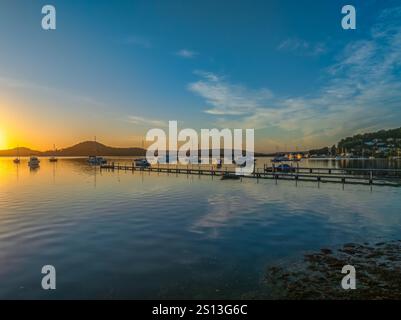 Alba sull'acqua di Brisbane, con cieli prevalentemente limpidi e una piccola nuvola luminosa alta intorno al Couche Park, Koolewong sulla costa centrale, NSW, Australi Foto Stock