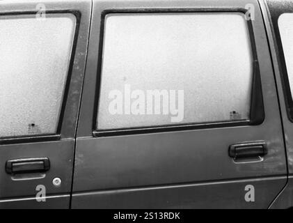 Motivi congelati: Vetro smerigliato e maniglia di un'auto parcheggiata Foto Stock