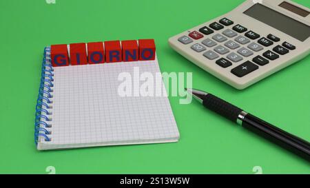 Parola singola DA GIORNO scritta su cubi di legno con sfondo verde e cancelleria da ufficio. Foto Stock