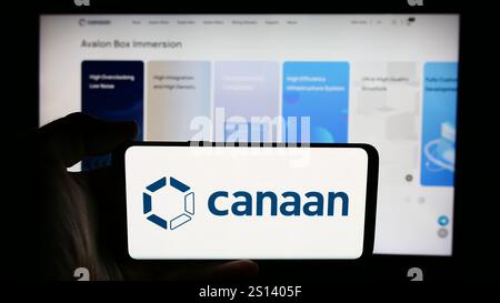 In questa immagine, una persona ha in mano un cellulare con il logo della società cinese di hardware per computer Canaan Inc. Davanti alla pagina Web aziendale. Foto Stock