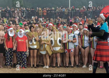 Centinaia di persone, molte in festa, proteste fognarie e costumi di beneficenza, si allineano prima di correre in mare sulla spiaggia di Exmouth durante l'annuale Christmas Day Swim, Devon, Regno Unito, 25 dicembre 2024. Foto Stock