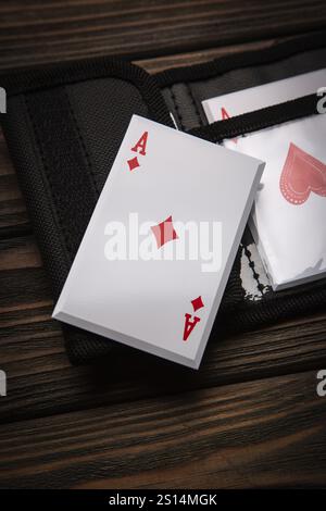Una serie di quattro assi da un mazzo di carte da gioco, tra cui picche, cuori, mazze e diamanti, sono visualizzati su una superficie di legno accanto a una scheda nera Foto Stock