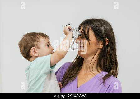 Optometrista che regge una cornice di prova e gioca con un paziente bambino Foto Stock
