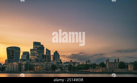 Mentre il sole tramonta dietro la City di Londra, gli uffici della città si illuminano, creando una giustapposizione tra il moderno e il vecchio Foto Stock