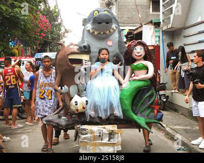 Malabon, Filippine. 31 dicembre 2024. Un'effigie di Jabberjaw o di uno squalo comico viene sfilata in strada mentre una bambina carina si siede davanti a essa. I residenti di Barangay Tañong a Malabon tengono la loro parata annuale di effigie la vigilia di Capodanno. La sfilata presenta effigie piene di firecracker. Credito: SOPA Images Limited/Alamy Live News Foto Stock