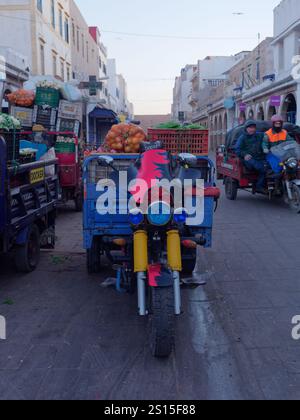 Biciclette a motore che trasportano carretti di prodotti nel mercato della Medina al mattino. Essaouira, 31 dicembre 2024 Foto Stock