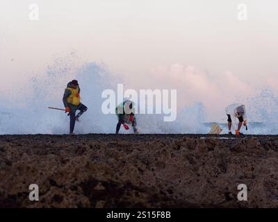 Fisherman on the Rocks as Wave crash in, nella città di Essaouira, 31 dicembre 2024 Foto Stock