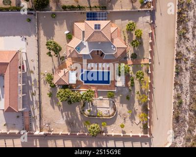 Vista a volo d'uccello di una villa in stile mediterraneo con piscina privata, ampio patio e giardino paesaggistico sotto il cielo limpido. Foto Stock