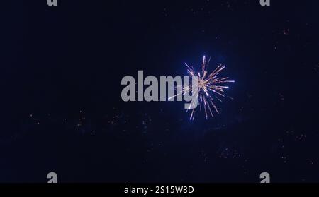 Incredibile spettacolo di fuochi d'artificio catturato durante le celebrazioni di Capodanno 2025, illuminando il cielo notturno su un quartiere residenziale Foto Stock
