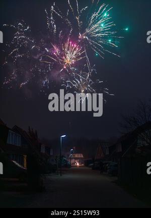 Incredibile spettacolo di fuochi d'artificio catturato durante le celebrazioni di Capodanno 2025, illuminando il cielo notturno su un quartiere residenziale Foto Stock