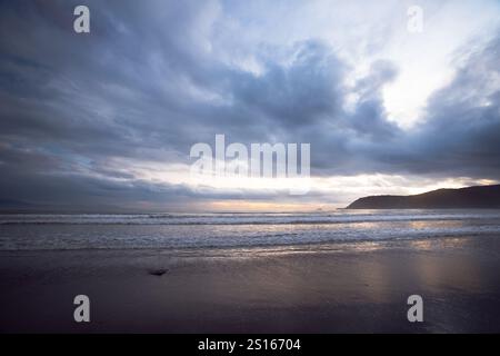 Immagine accattivante di una costa al crepuscolo, caratterizzata da un cielo spettacolare pieno di nuvole scure e testurizzate. Una luce soffusa e diffusa irrompe nel clou Foto Stock