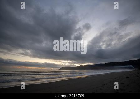 Immagine accattivante di una costa al crepuscolo, caratterizzata da un cielo spettacolare pieno di nuvole scure e testurizzate. Una luce soffusa e diffusa irrompe nel clou Foto Stock