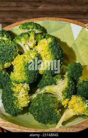 Pezzi di broccoli freschi nel recipiente su un tavolo di legno Foto Stock
