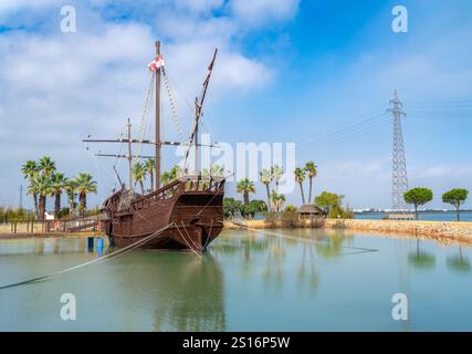 Una replica dettagliata di Nina, una nave caravella in legno, ormeggiata al Caravel Dock Museum. La nave è circondata da palme e acque calme, con un cle Foto Stock