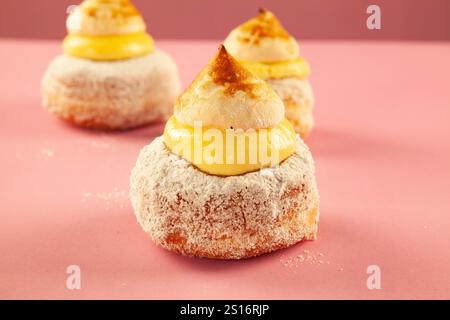 Ciambelle Scone con gelatina di fragole e meringa e crema alla vaniglia su sfondo rosa. Foto Stock