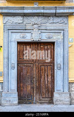 Porta medievale in legno con decorazioni in pietra in un antico edificio. Foto Stock