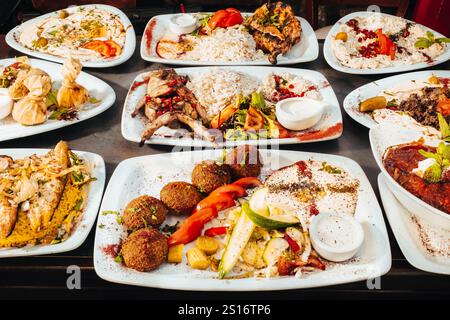 Un'abbondante festa mediterranea con quaglia grigliata, falafel, hummus, riso e insalate fresche, presentato in un elegante layout a banchetto. Foto Stock