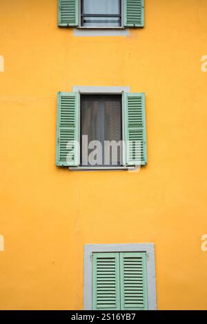 Facciata di un vecchio edificio giallo con finestre con persiane Foto Stock