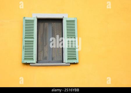 Facciata di un vecchio edificio giallo con finestre con persiane Foto Stock