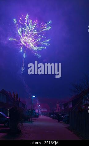 Incredibile spettacolo di fuochi d'artificio catturato durante le celebrazioni di Capodanno 2025, illuminando il cielo notturno su un quartiere residenziale Foto Stock