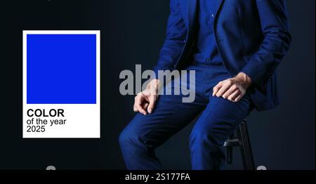 Uomo con elegante tuta blu su sfondo scuro. Colore dell'anno 2025 Foto Stock