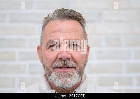 Ritratto ravvicinato di un uomo maturo con barba grigia e un sorriso sicuro e delicato. Foto Stock