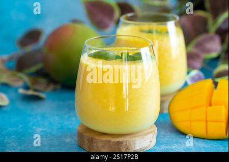 Freschi lassi di mango in bicchieri su sfondo blu con spazio per le copie. Indiano sana detossica ayurvedica bevanda fredda con mango. Lassi di freschezza a base di yogur Foto Stock